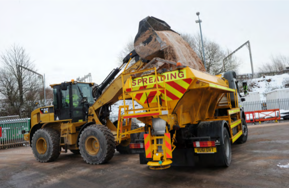 ½ Material is loaded on to a spreading machine at a depot.