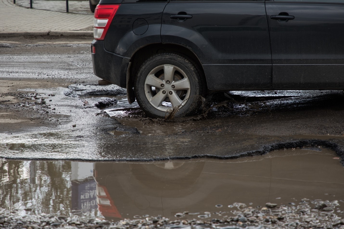 Main image: car passing through large pothole on UK Road; credit: Shutterstock